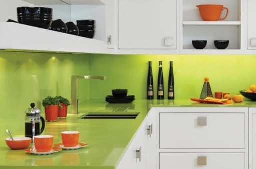 Le comptoir et le tablier d'une teinte citron vert clair sont parfaits en combinaison avec des façades de cuisine blanches et des plats orange.