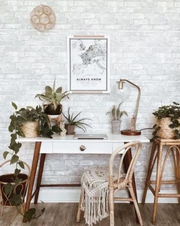 Bureau à domicile boho chic avec table en bois rétro, tapis boho, artisanat mural, beaucoup de plantes d'intérieur: cactus et plantes succulentes